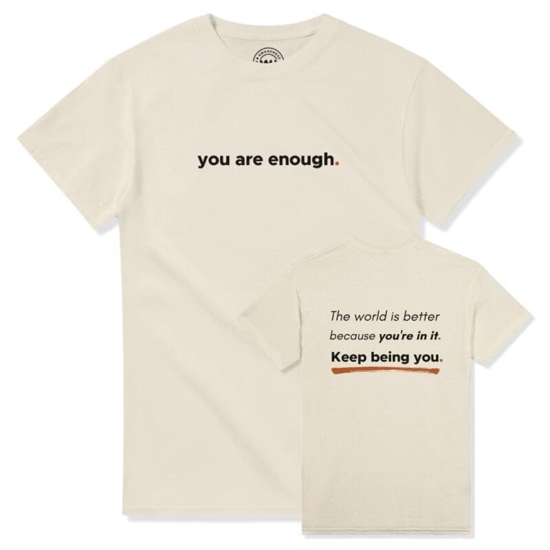 Front and back view of the cream natural cream "You Are Enough" streetwear crew neck t-shirt. The front features a clean, minimalist print reading "you are enough." The back panel displays the full quote layout reading: "The world is better because you're in it. Keep being you." underlined by an earthy terracotta orange accent brushstroke.