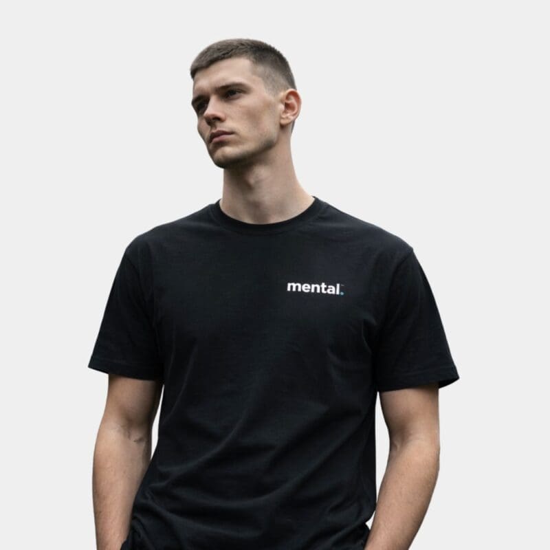 Man wearing black 'mental.' t-shirt, looking thoughtful.