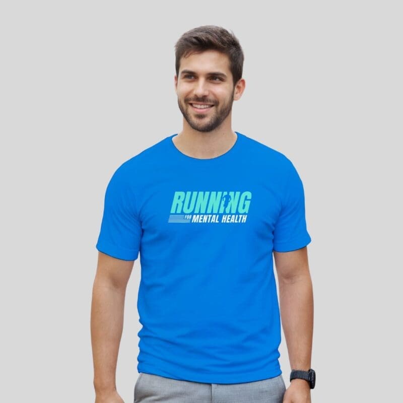 Man wearing a royal blue “Running for Mental Health” performance T-shirt, standing and smiling with the design clearly visible on the front.