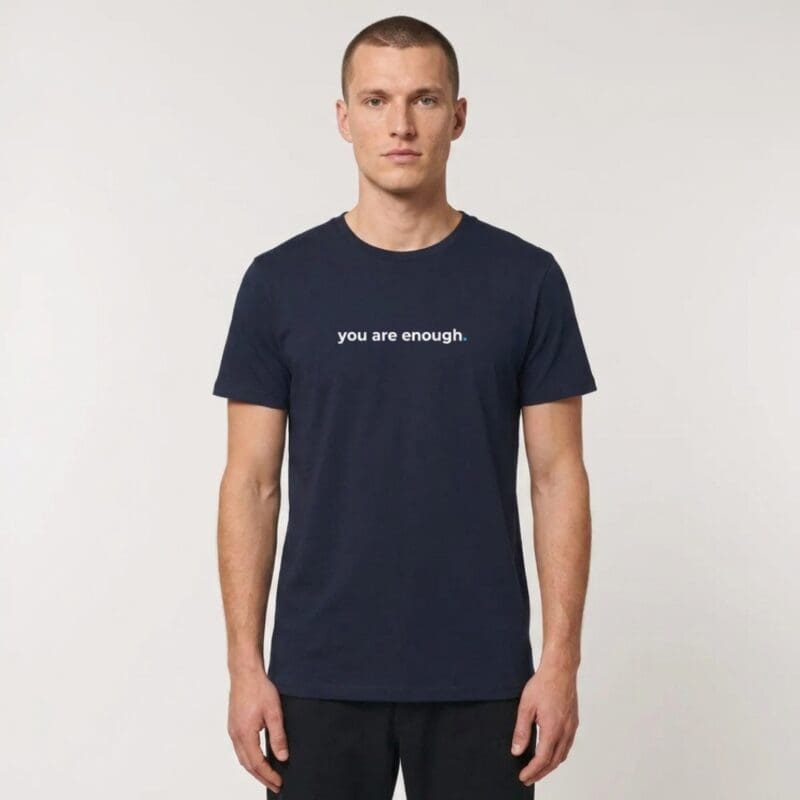 Male model wearing a navy MMH Clothing “You Are Enough” organic recycled T-shirt in a clean studio setting. The front chest print reads “you are enough.” in white with a blue accent dot.