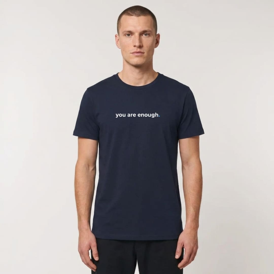 Male model wearing a navy MMH Clothing “You Are Enough” organic recycled T-shirt in a clean studio setting. The front chest print reads “you are enough.” in white with a blue accent dot.