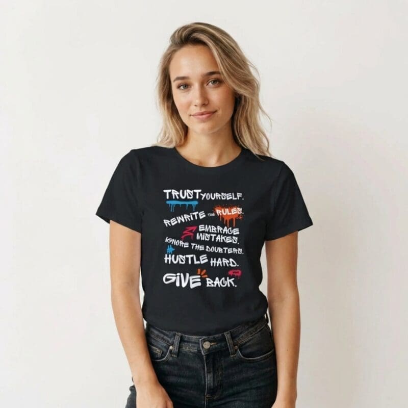 Female model wearing the MMH Clothing “Rules For Life” women’s black T-shirt. The front design features a bold graffiti-style rule list with the phrases “Trust Yourself,” “Rewrite the Rules,” “Embrace Mistakes,” “Ignore the Doubters,” “Hustle Hard,” and “Give Back” in white text with blue, red and orange accent details.