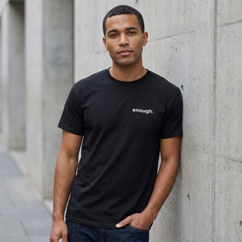 Man in black 'enough.' T-shirt by wall