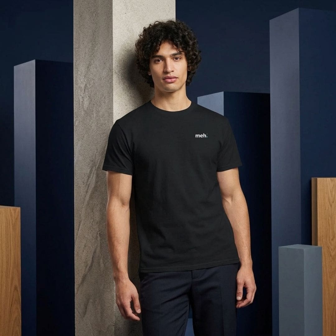 Man wearing black ‘meh.’ slogan T-shirt indoors