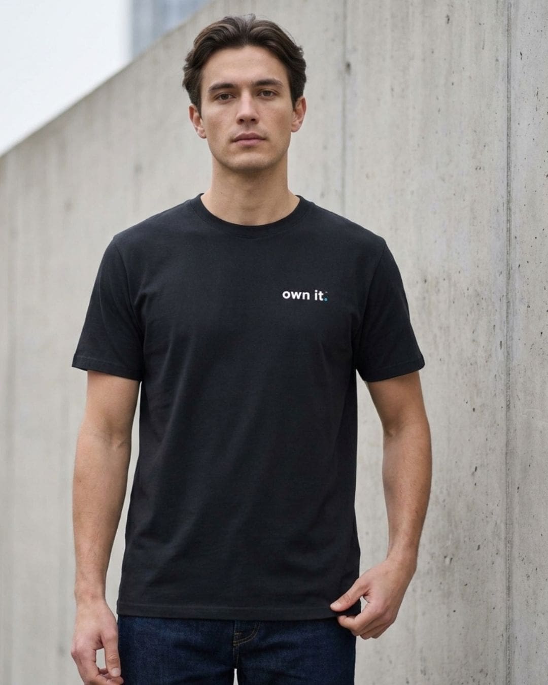 Man wearing black slogan T-shirt by concrete wall